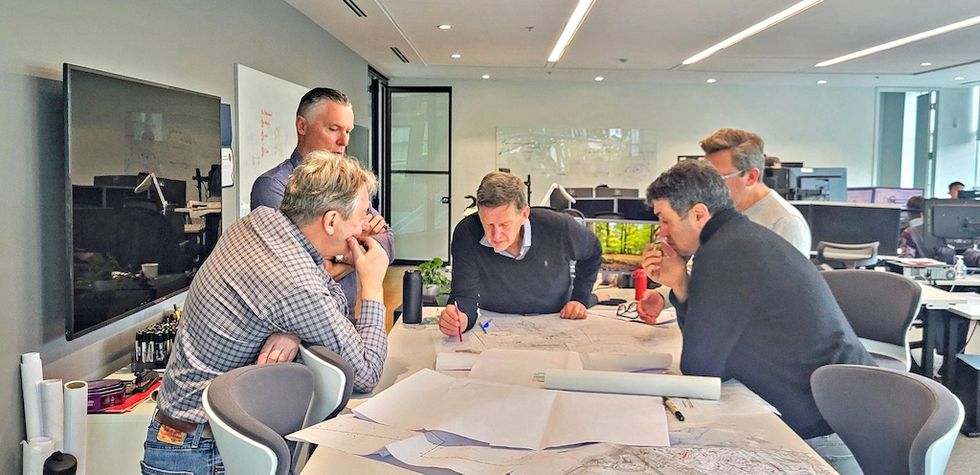 Five men discussing architectural plans in a modern office.