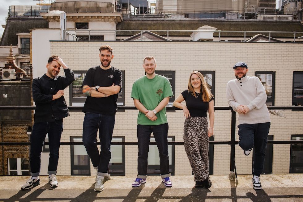 Five people from Factory Immersive smiling on a rooftop with a cityscape backdrop.