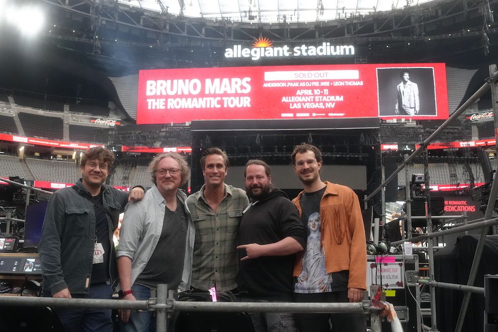 Five people posing at Allegiant Stadium with a "Bruno Mars Tour" sign in the background.