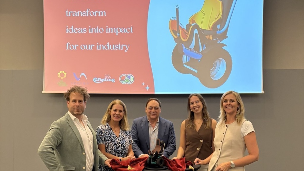 Five people smiling in front of a presentation screen with a product design displayed.