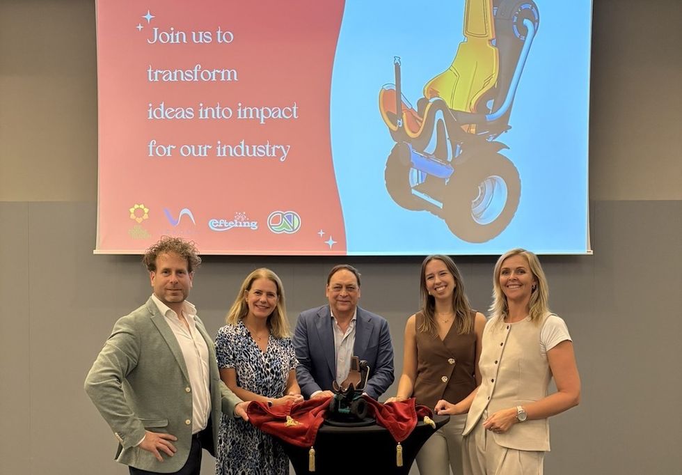 Five people smiling in front of a presentation screen with a product design displayed.