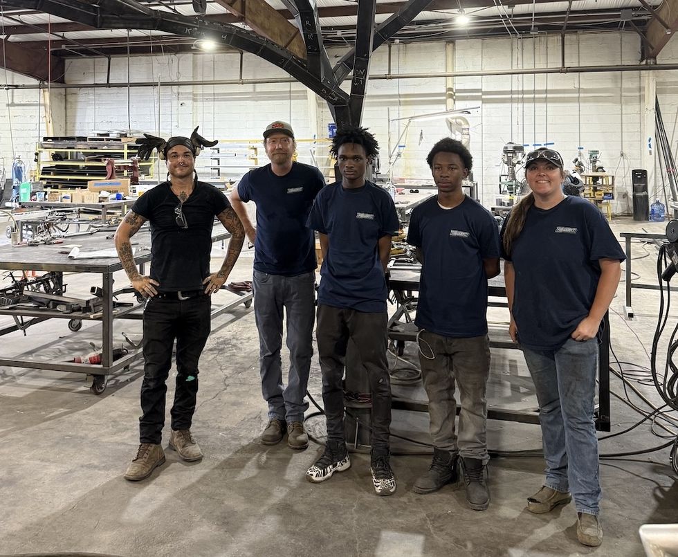 Five people standing in Downtown FabWorks workshop, surrounded by metal equipment.