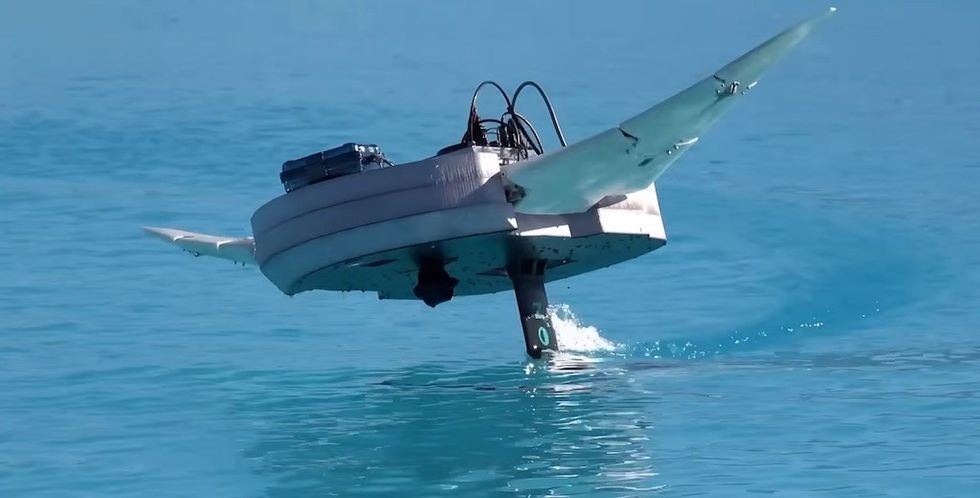 Flying saucer-shaped drone skimming over water.