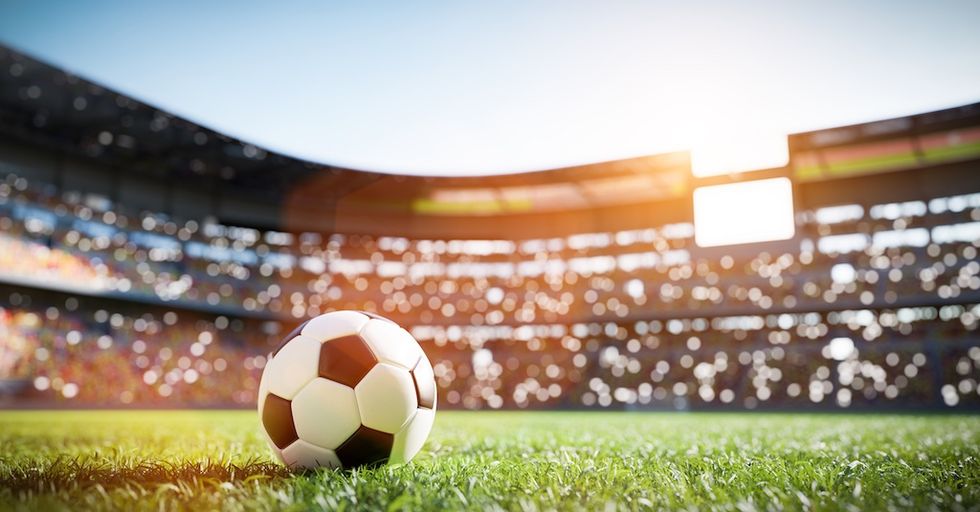 football on a sunlit field in a large stadium.