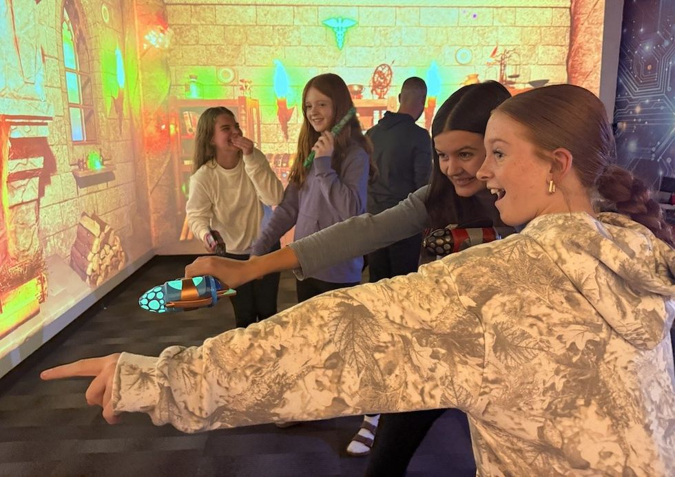 Four girls having fun playing a video game with projection walls.
