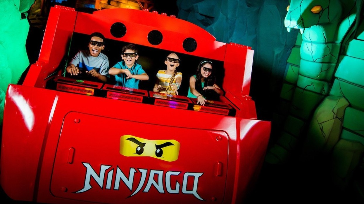 Four kids enjoy a 3D Ninjago ride at an amusement park, wearing 3D glasses.
