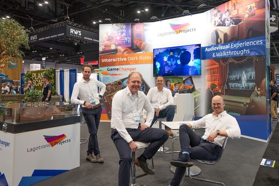 Four men at a trade fair booth for interactive audiovisual experiences.