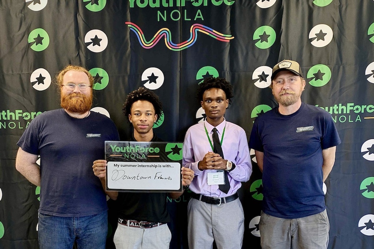 Four men pose at a YouthForce NOLA event; one holds an internship sign reading Downtow FabWorks