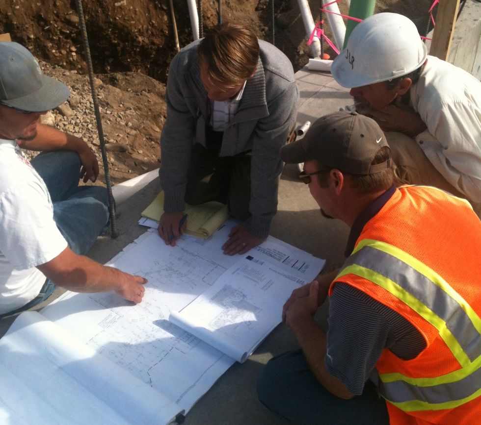 Four people discuss construction plans on-site.