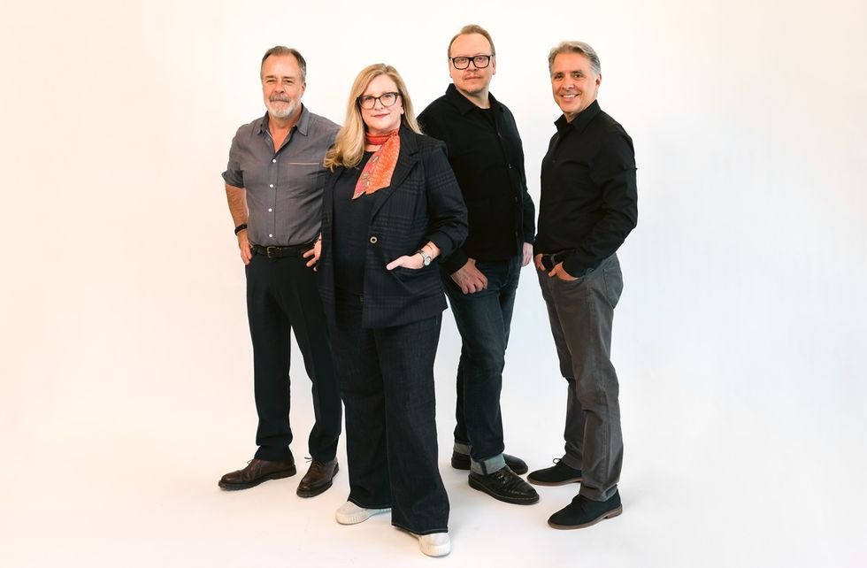 Four people from BRC Imagination Arts standing against a plain white background, smiling and posing confidently.
