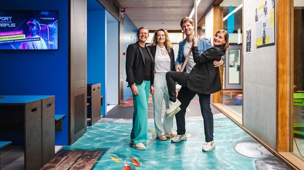 Four people posing happily in a modern hallway with a 3D floor design.