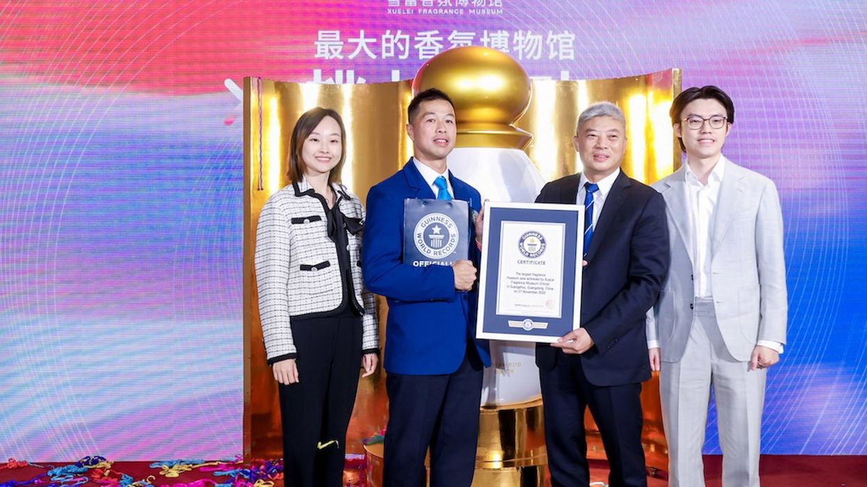 Four people posing with a Guinness World Record certificate on a colorful stage.