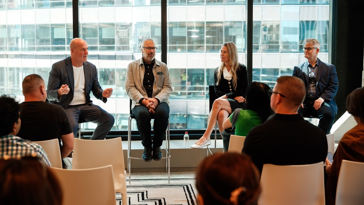 Four people speaking on a panel in front of an audience in a modern, glass-walled room at the Fast Company Innovation Festival.