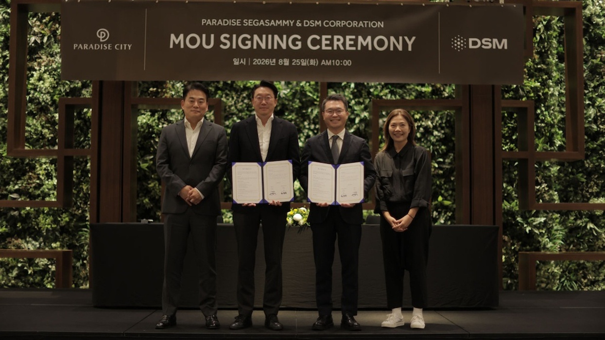 Four people standing at a signing ceremony with documents and a green backdrop.