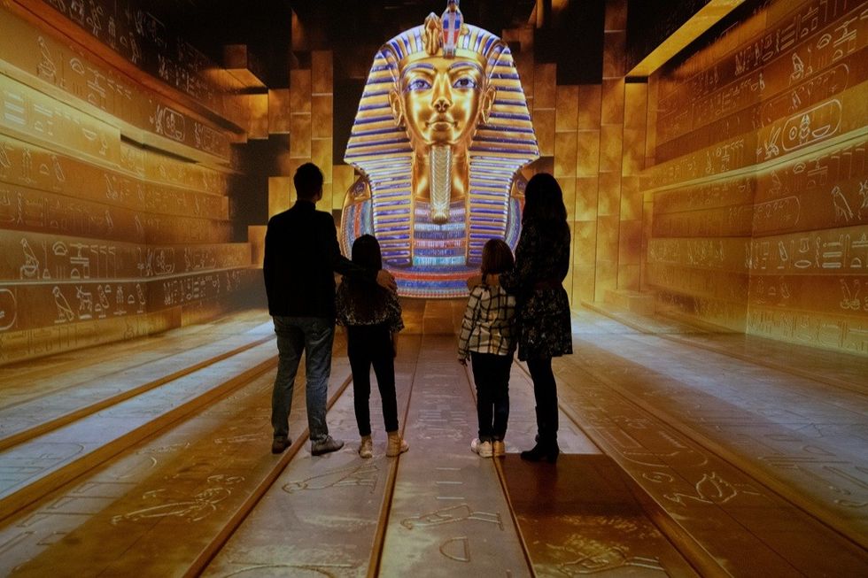 Four people viewing a large digital Pharaoh display in an immersive exhibit.