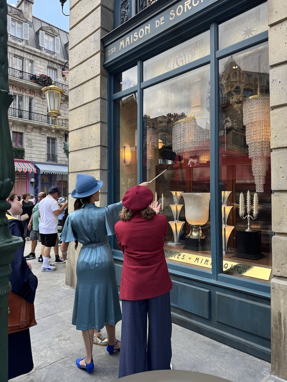 French witches showing guests the interactive windows in Place Cacheé Wizarding World of Harry Potter Ministry of Magic Universal Epic Universe