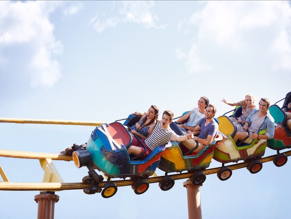 Friends cheering and riding roller coaster at amusement park feasibility