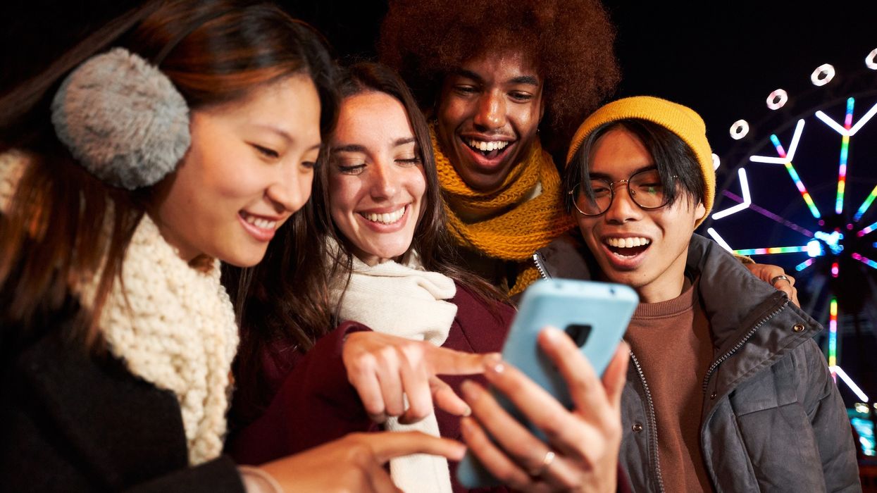 friends-gather-round-phone-at-winter-fair