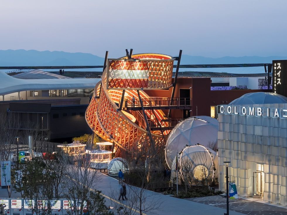 Futuristic architectural pavilion with glowing spiral structure and dome at twilight.