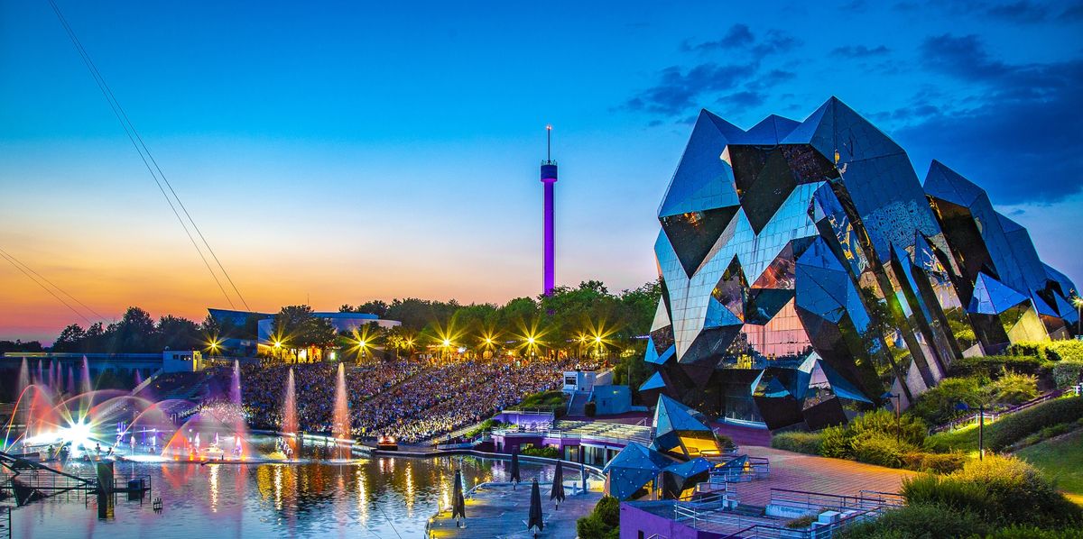 Futuristic architecture and colorful fountains at sunset in a vibrant amusement park called Futuroscope