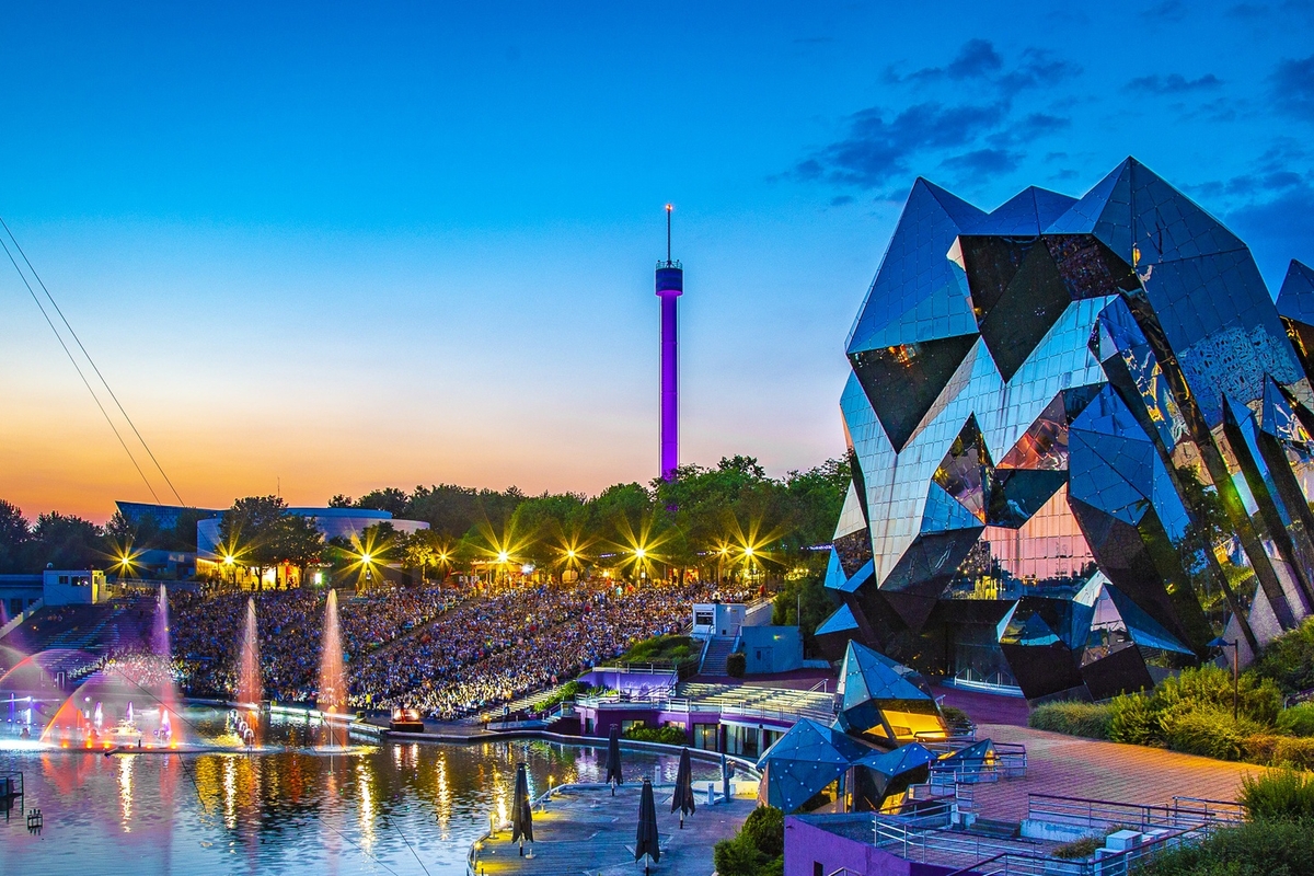 Futuristic architecture and colorful fountains at sunset in a vibrant amusement park called Futuroscope