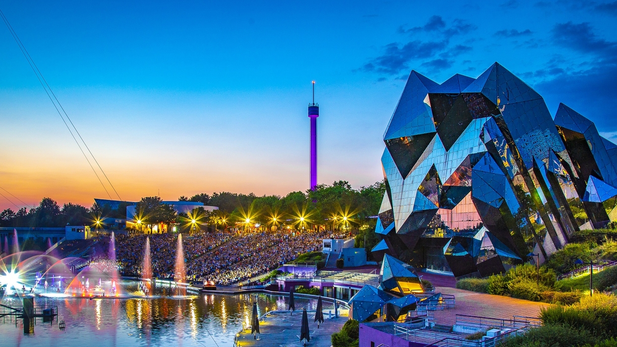 Futuristic architecture and colorful fountains at sunset in a vibrant amusement park called Futuroscope