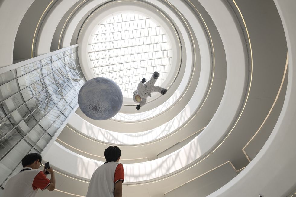 Futuristic atrium at the Hainan Science Museum with an astronaut installation and a blue planet.