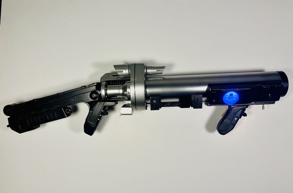 Futuristic black and silver tube-shaped device with a glowing blue emblem.