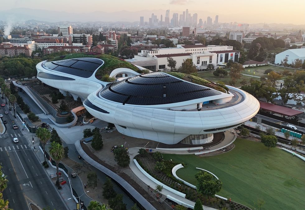 Futuristic building called the Lucas Museum of Narrative Art with curved design and green roof, city skyline in the background.