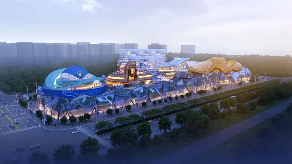 Futuristic building complex with vibrant blue and gold structures, surrounded by greenery.