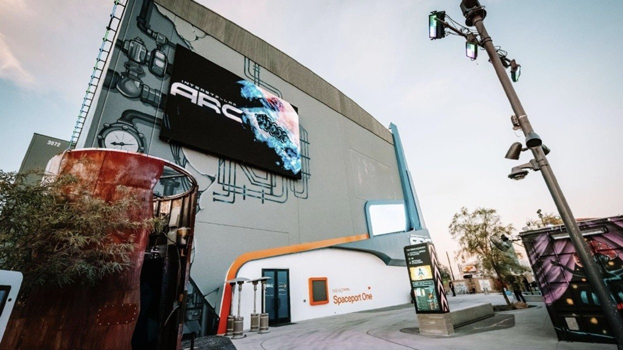 Futuristic building with large screen and industrial design elements at sunset.