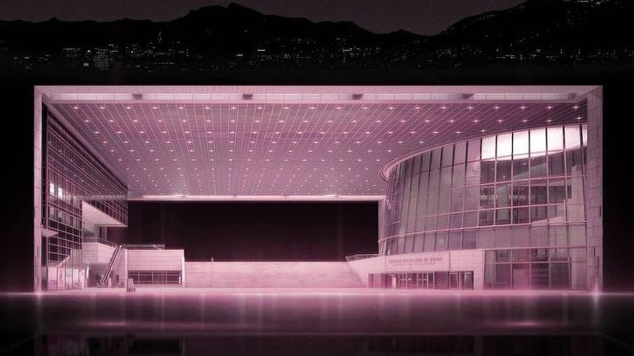 Futuristic building with pink lighting at night with mountainous backdrop.
