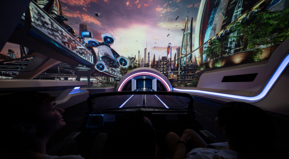 Futuristic city skyline viewed from inside a simulated vehicle ride with flying cars.