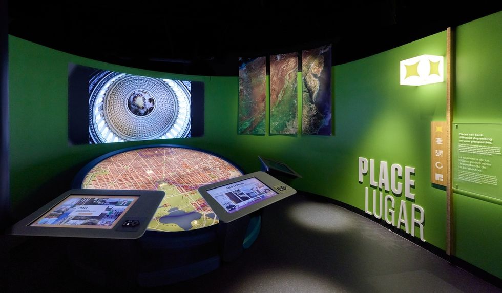 Futuristic exhibit room at the National Geographic Museum of Exploration, with interactive screens and wall projections labeled "PLACE LUGAR."
