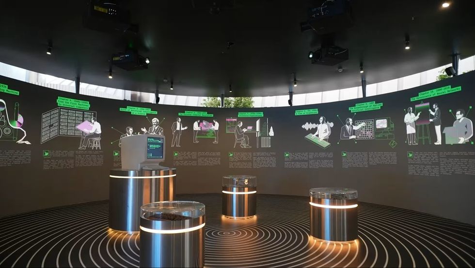Futuristic exhibit room with illustrated timeline on curved walls and circular displays at ALEM AI International Center for Artificial Intelligence
