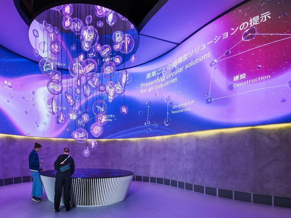 Futuristic exhibit with hanging LED bubbles, purple lighting, and people observing.
