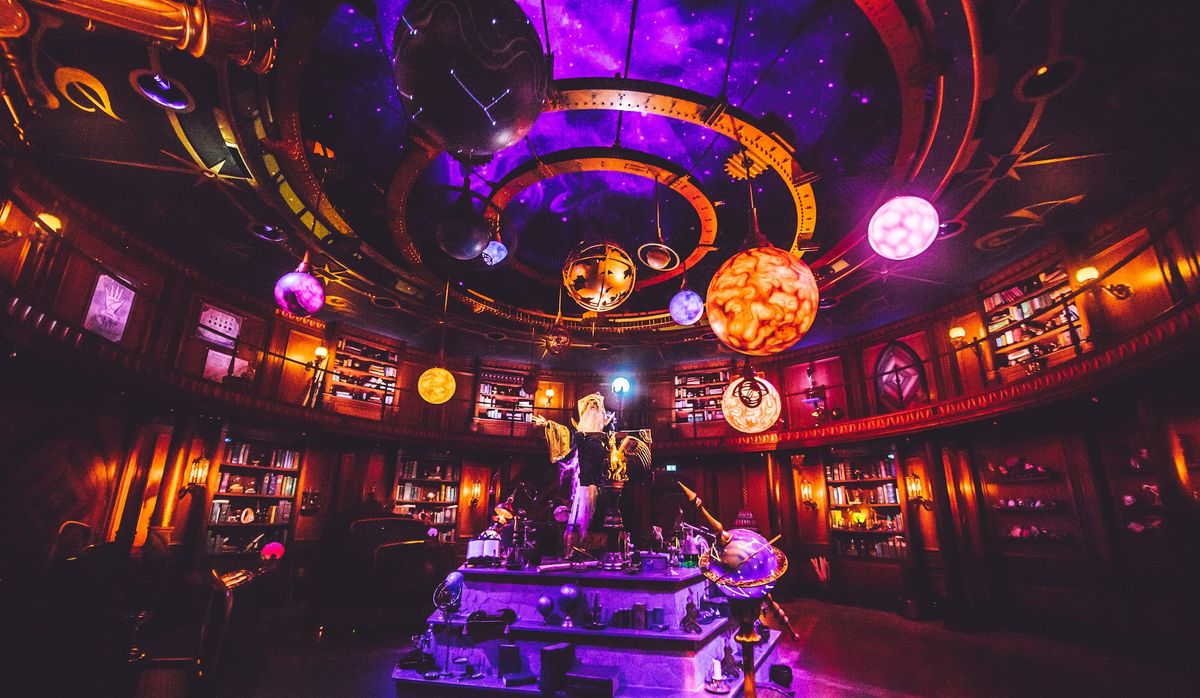 Futuristic, glowing library with planets and celestial decorations on the ceiling.