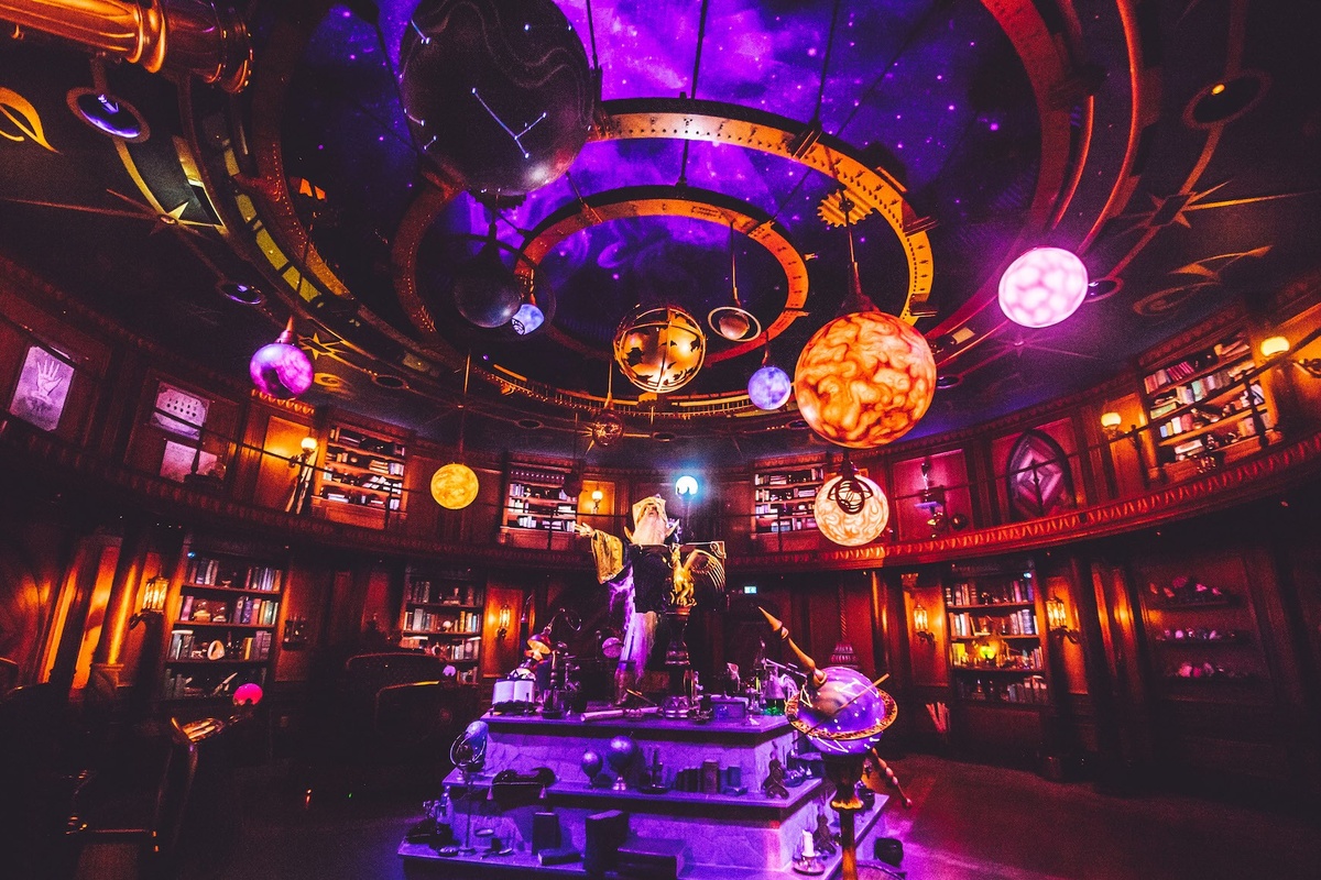 Futuristic, glowing library with planets and celestial decorations on the ceiling.