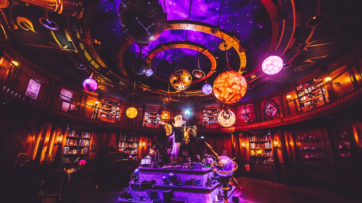 Futuristic, glowing library with planets and celestial decorations on the ceiling.