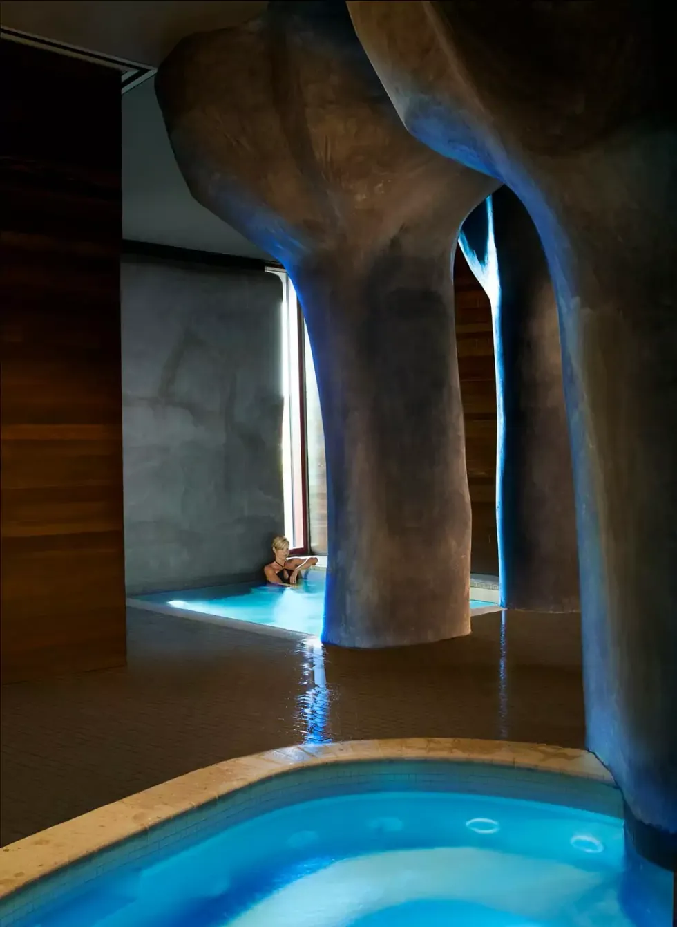 Futuristic indoor pool with tree-like pillars and blue lighting.