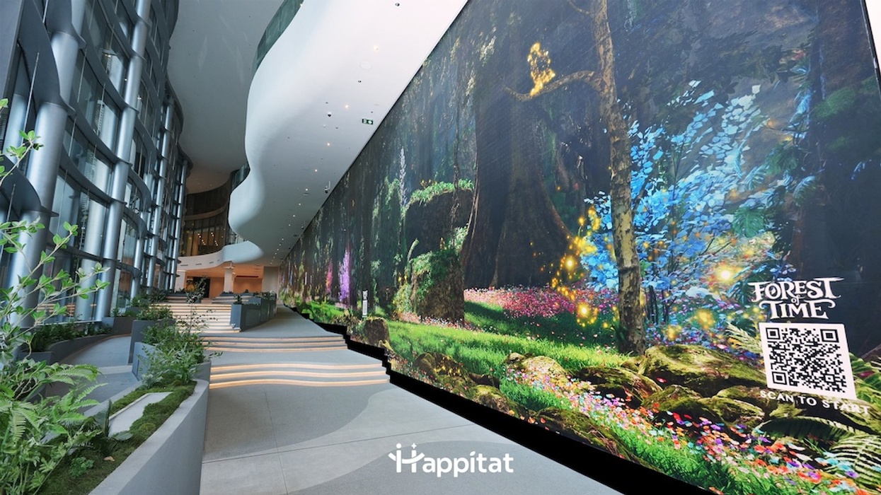 Futuristic lobby at Happitat with a large digital forest mural, Forest of Time, and QR code.