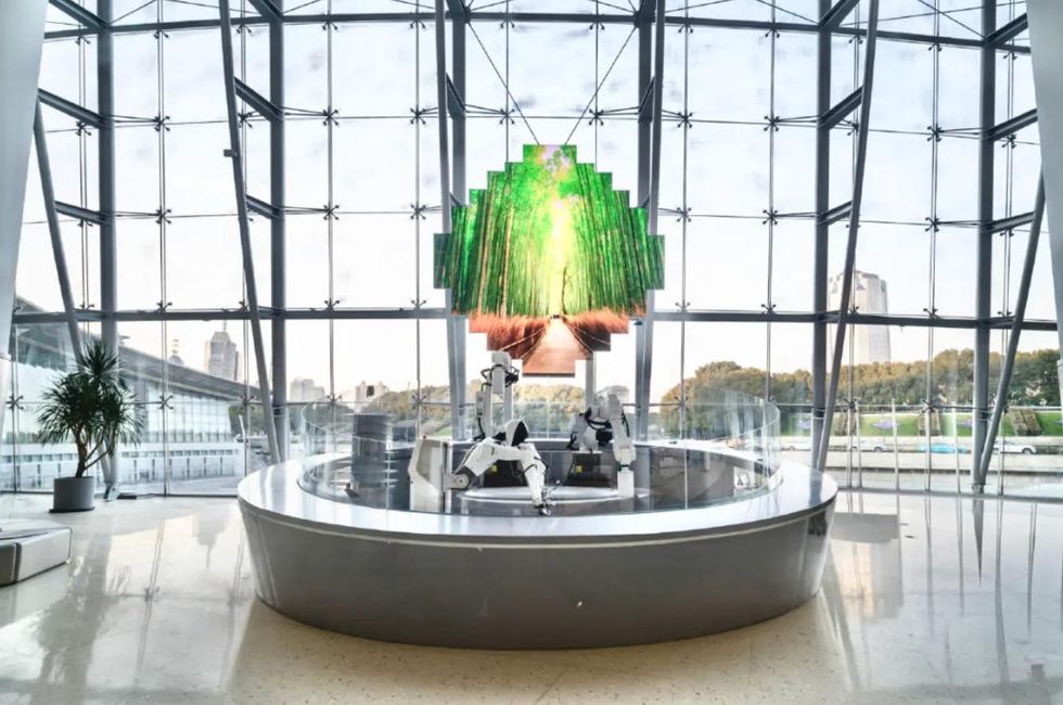 Futuristic lobby with large windows and robotic installations under a digital tree display.