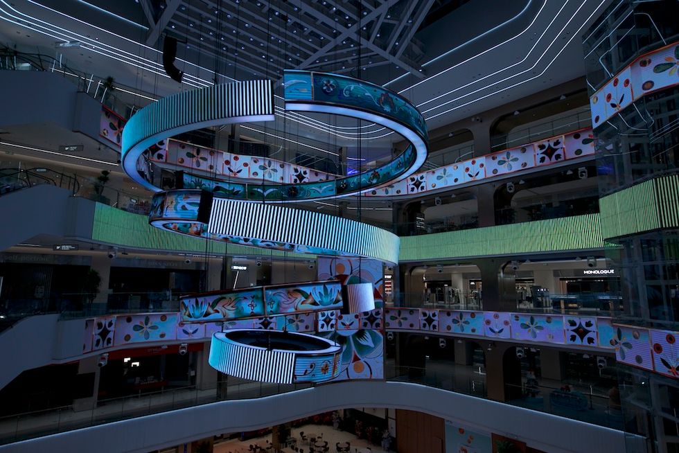 Futuristic mall interior with colorful LED spiral and floral patterns.