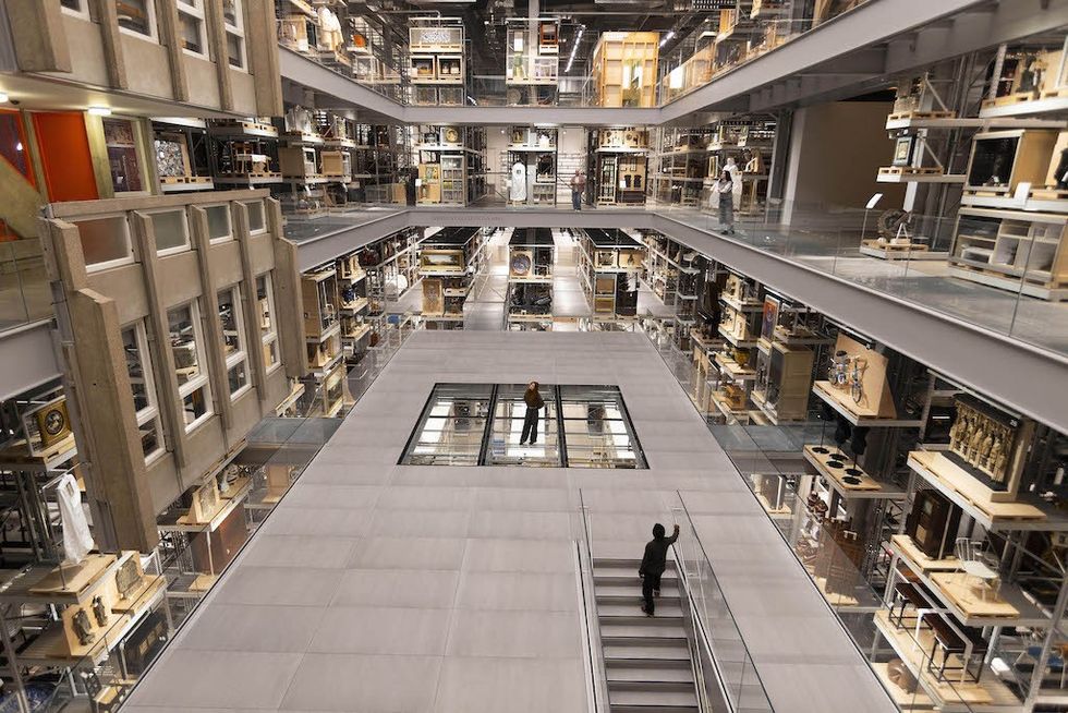 Futuristic multi-level museum interior with shelves of artifacts and visitors, V&A East Storehouse