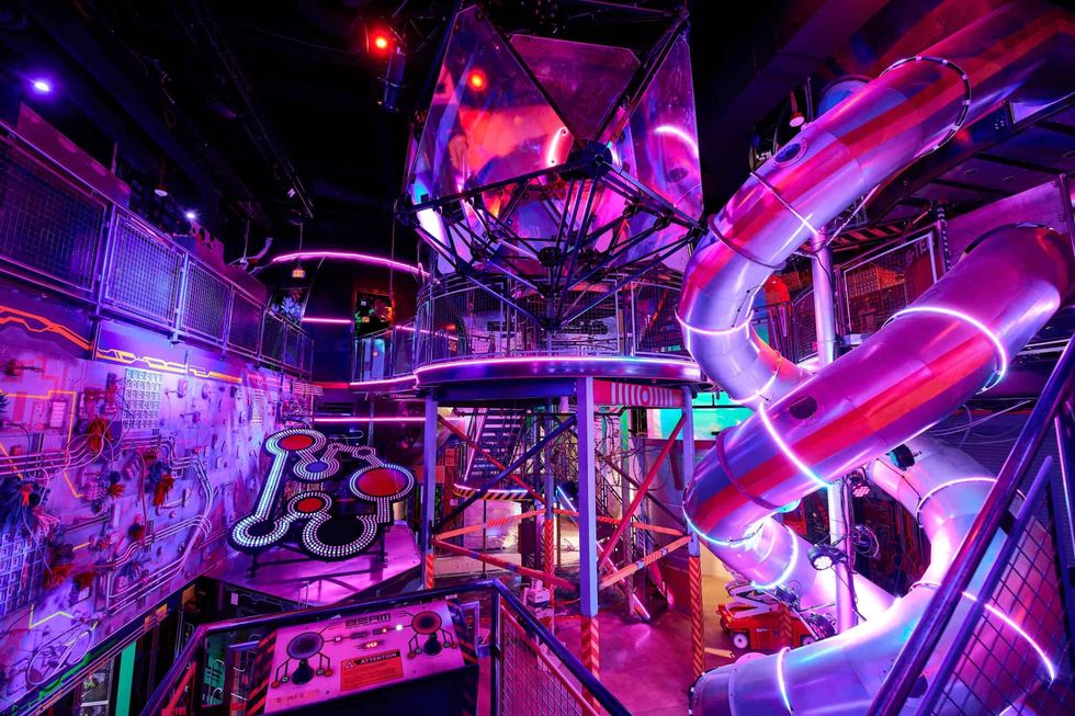 Futuristic, neon-lit indoor playground with slides and colorful lights at Omega Mart