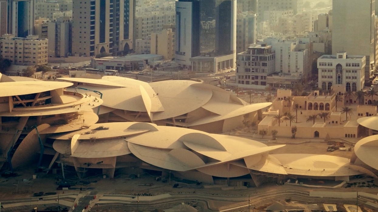 Futuristic, overlapping disc-shaped building in a cityscape with high-rises in the background.