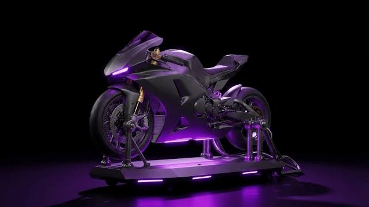 Futuristic purple-lit motorcycle displayed on a stand in a dark room.
