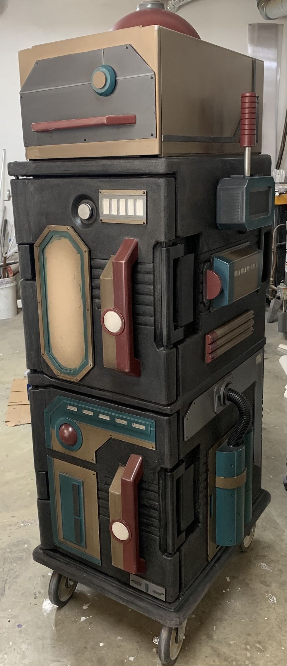 Futuristic, retro-styled cart with metallic panels and colorful levers on wheels.