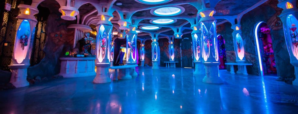 Futuristic room with glowing columns and blue ambient lighting.