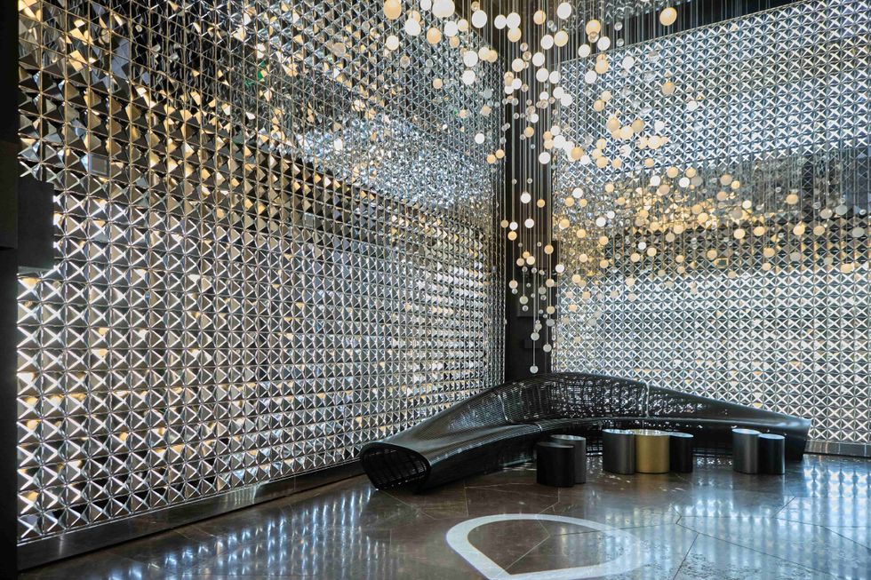 Futuristic room with mirrored walls and hanging lights, featuring modern seating.